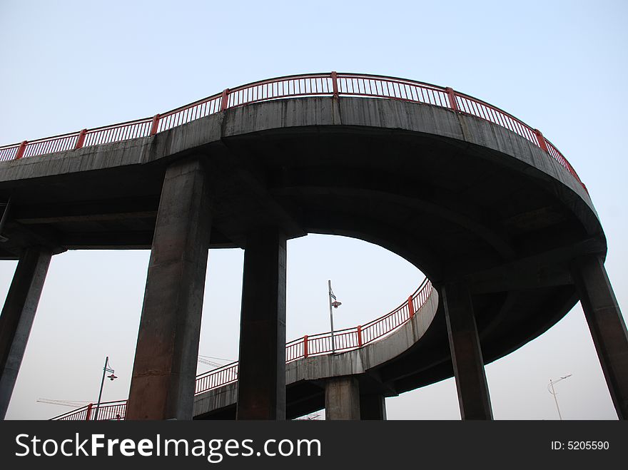 The curving footbridge attached to a steel bridge.