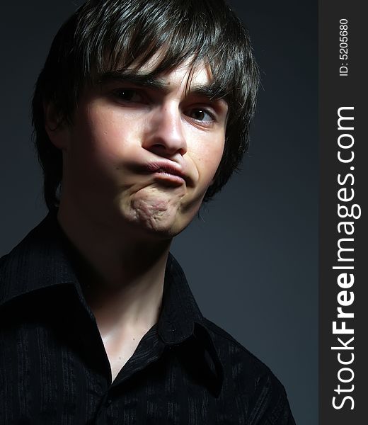 A portrait about a trendy cute young guy who is looking towards and he is pulling faces. He is wearing a stylish black shirt. A portrait about a trendy cute young guy who is looking towards and he is pulling faces. He is wearing a stylish black shirt.