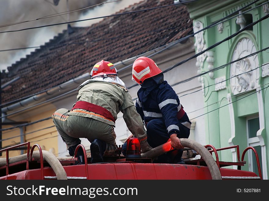 Two firemen in action on the roof of a fire truck. Two firemen in action on the roof of a fire truck