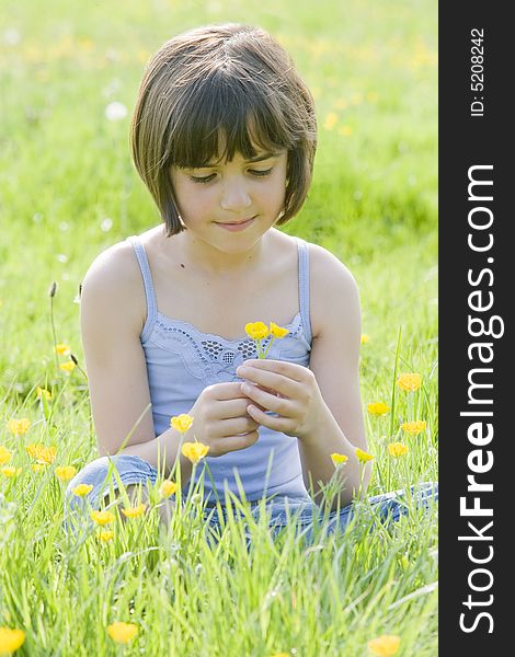 Young female child sitting cross legged in a field full of buttercups. Young female child sitting cross legged in a field full of buttercups