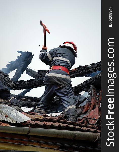 Fireman in action on the roof of a burning house