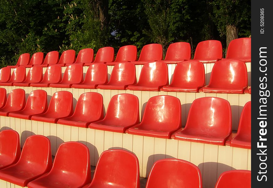 Red chairs situated in raw's on stadium