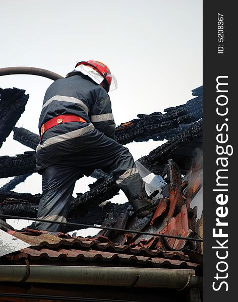 Fireman in action on the roof of a burning house