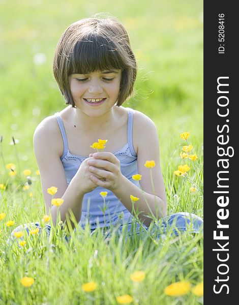 Young female child sitting cross legged in a field full of buttercups smiling. Young female child sitting cross legged in a field full of buttercups smiling