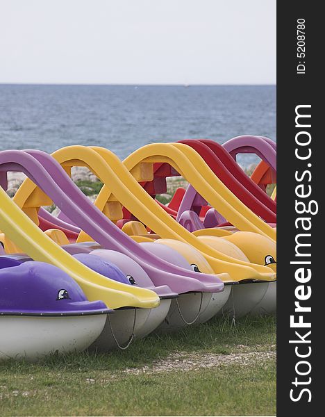 Dolphin-shaped water bicycles rowed at the edge of a sea