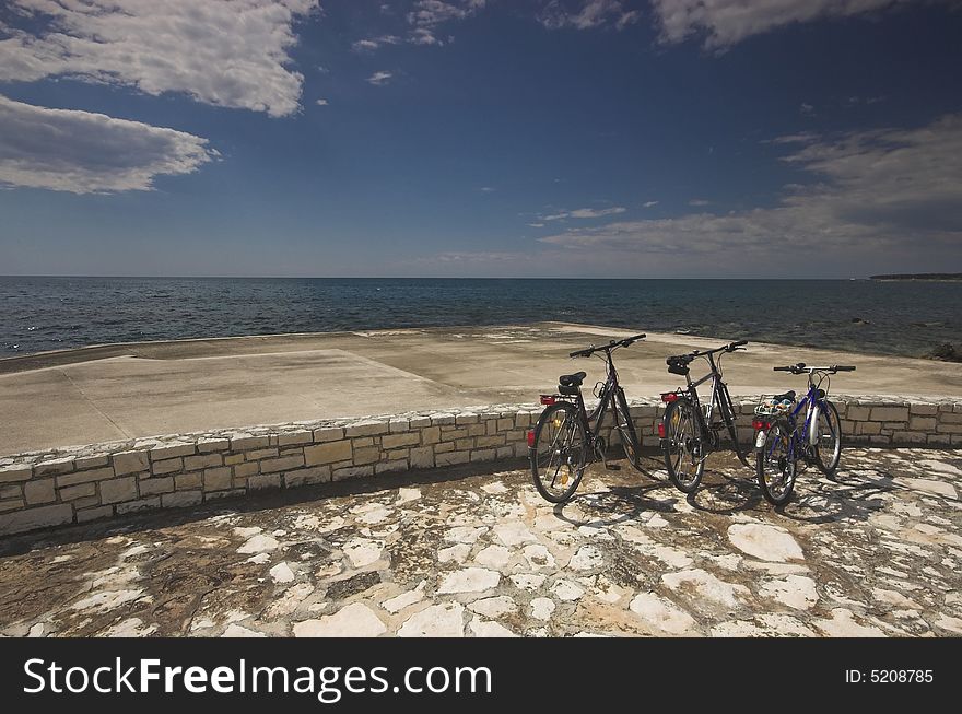 Three bicycles parked at the edge of a sea