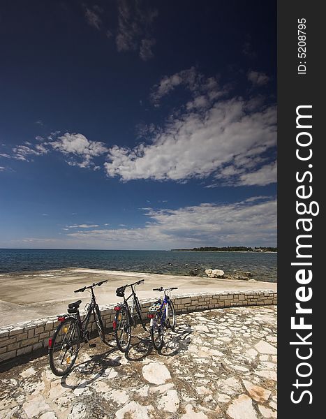 Three bicycles parked at the edge of a sea