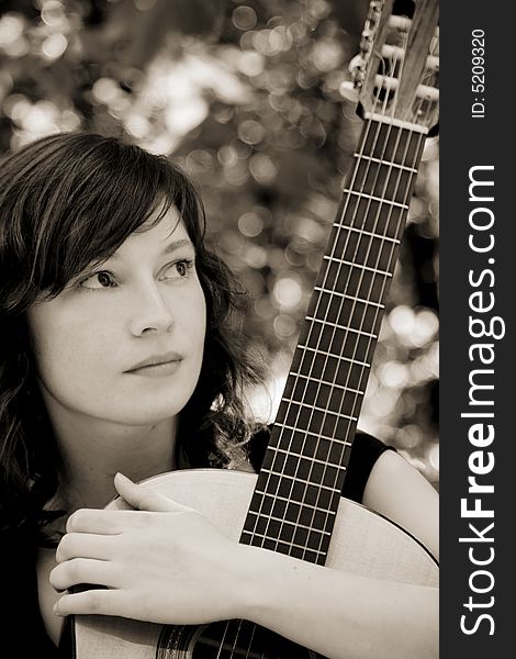 Young woman holding her classic guitar, sepia toned. Young woman holding her classic guitar, sepia toned.