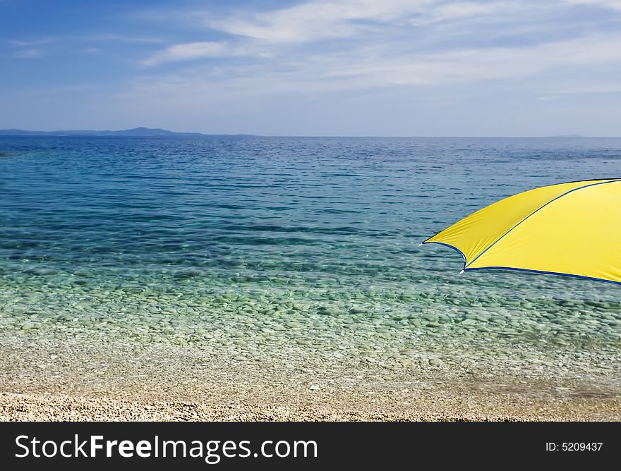 Part of a yellow umbrella on a secluded beach. Part of a yellow umbrella on a secluded beach.