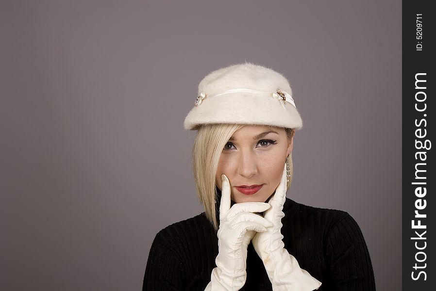 A blonde in a white fur hat and black turtleneck sweater with two white gloves. A blonde in a white fur hat and black turtleneck sweater with two white gloves