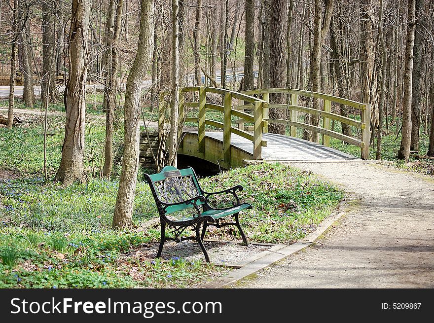 This is a park bench by a bridge. This is a park bench by a bridge