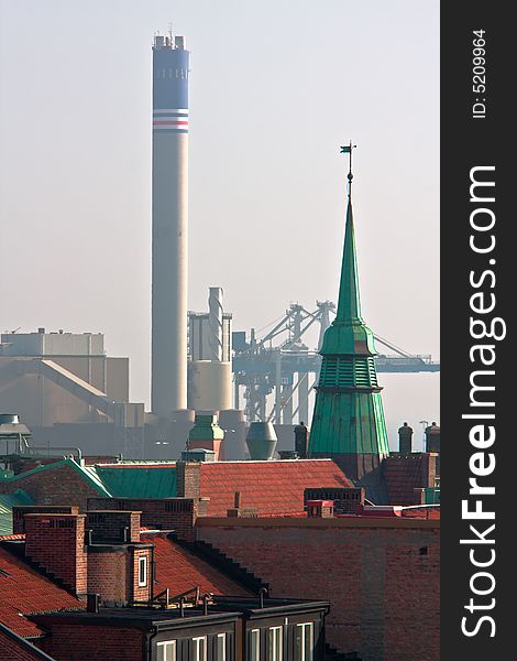 Contrast between urban rooftops and an industrial factory. Contrast between urban rooftops and an industrial factory