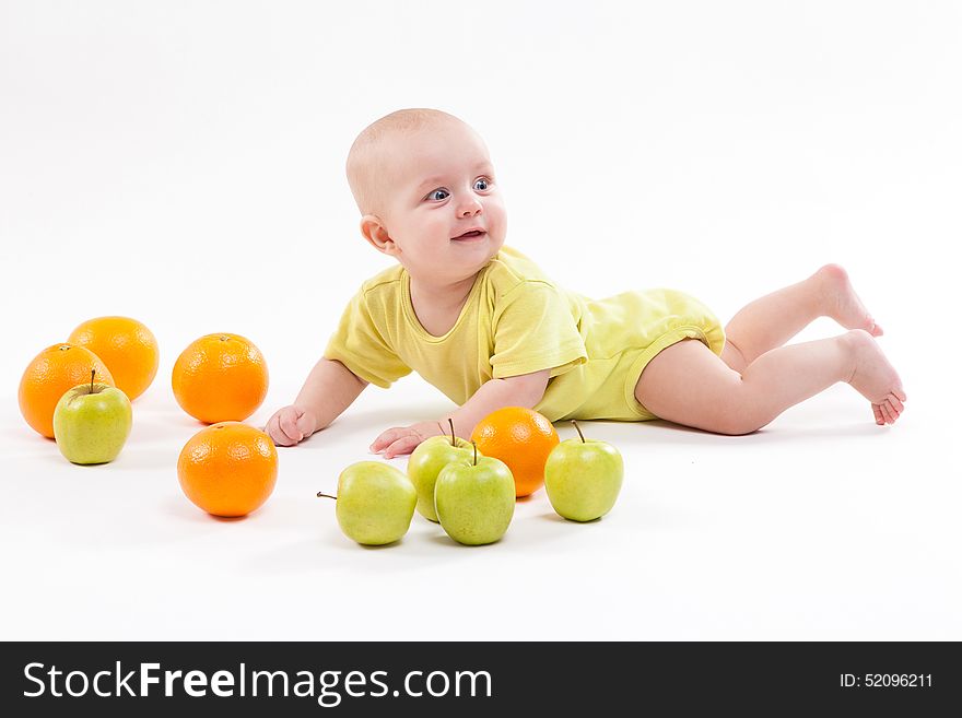 Cute surprised baby looks at green apple on a white background