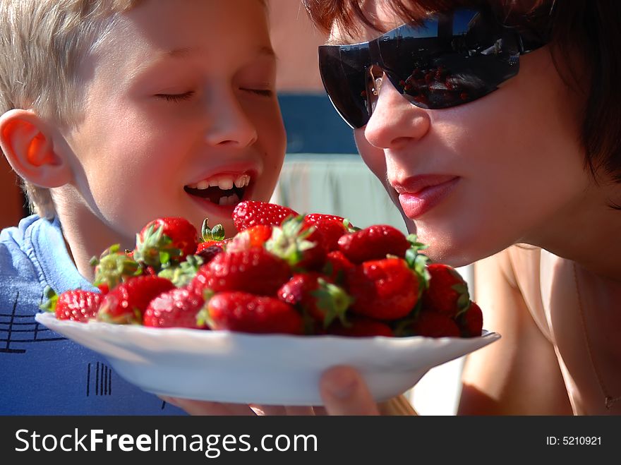 Mother and the son eat a strawberry