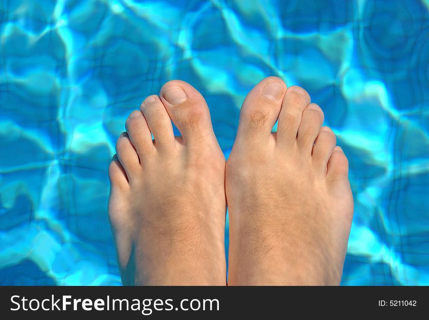 Feet in blue water on swimming pool