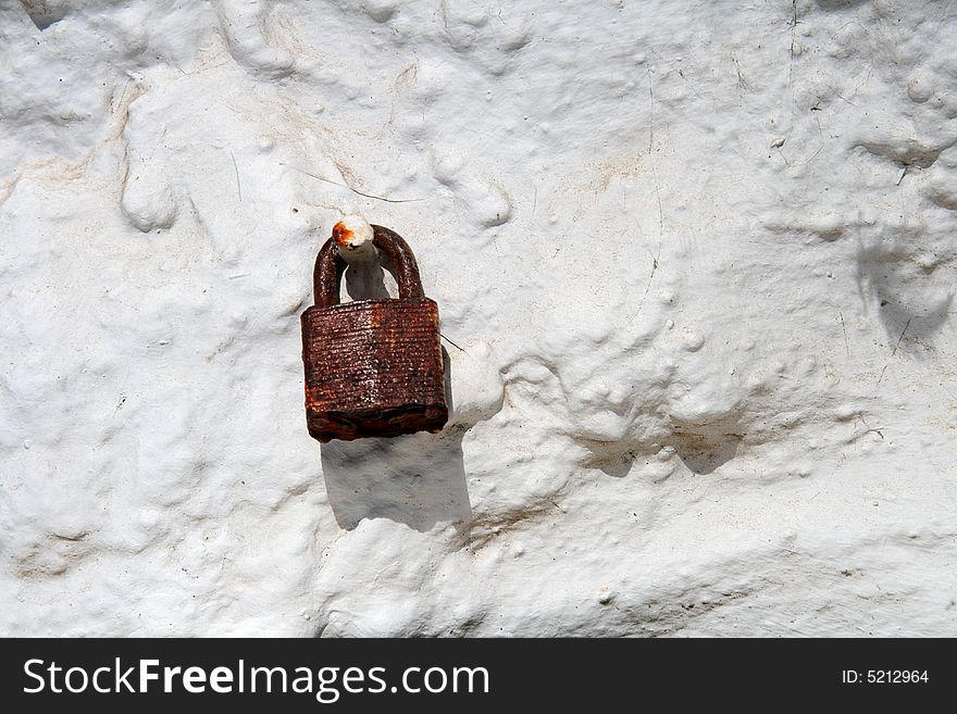 Rusty red padlock on old dirty white wall