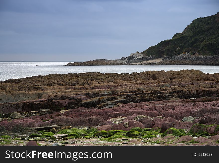 Sunshine sea view with overcast sky, low-tide beach, Cornwell, England