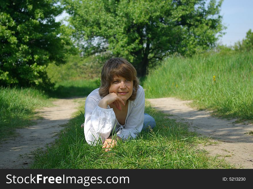 A young attractive woman sitting in a path on a warm summer day