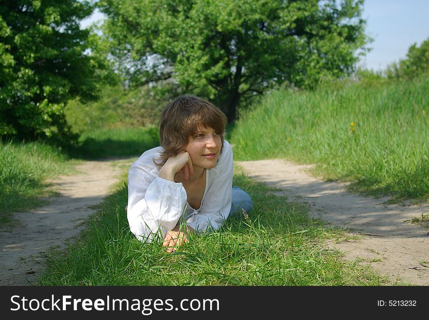 A young attractive woman sitting in a path on a warm summer day