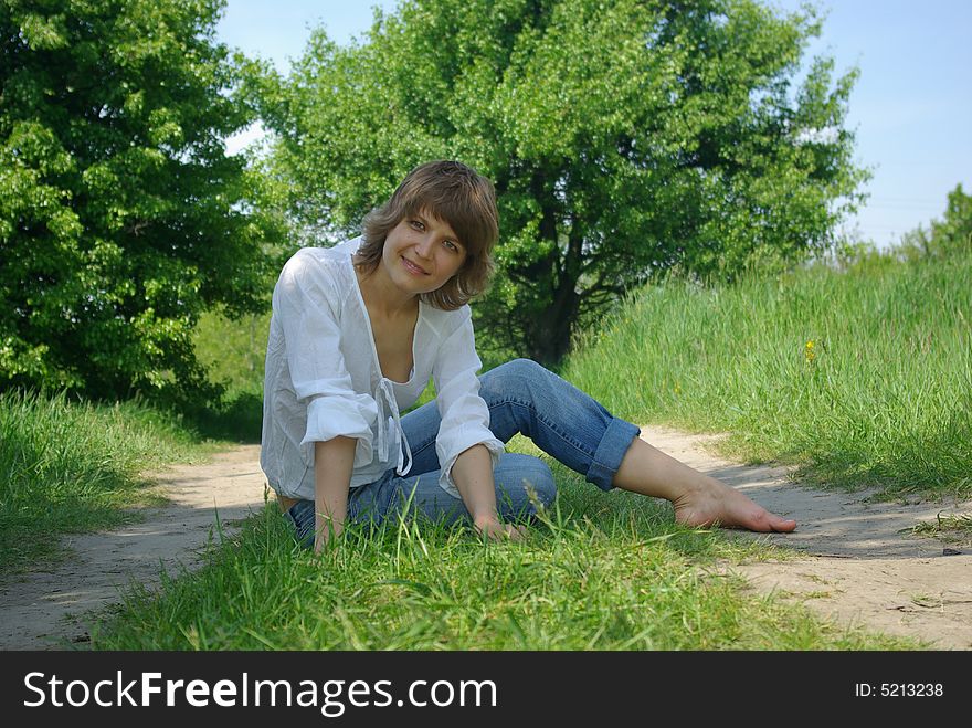 A young attractive woman sitting in a path on a warm summer day