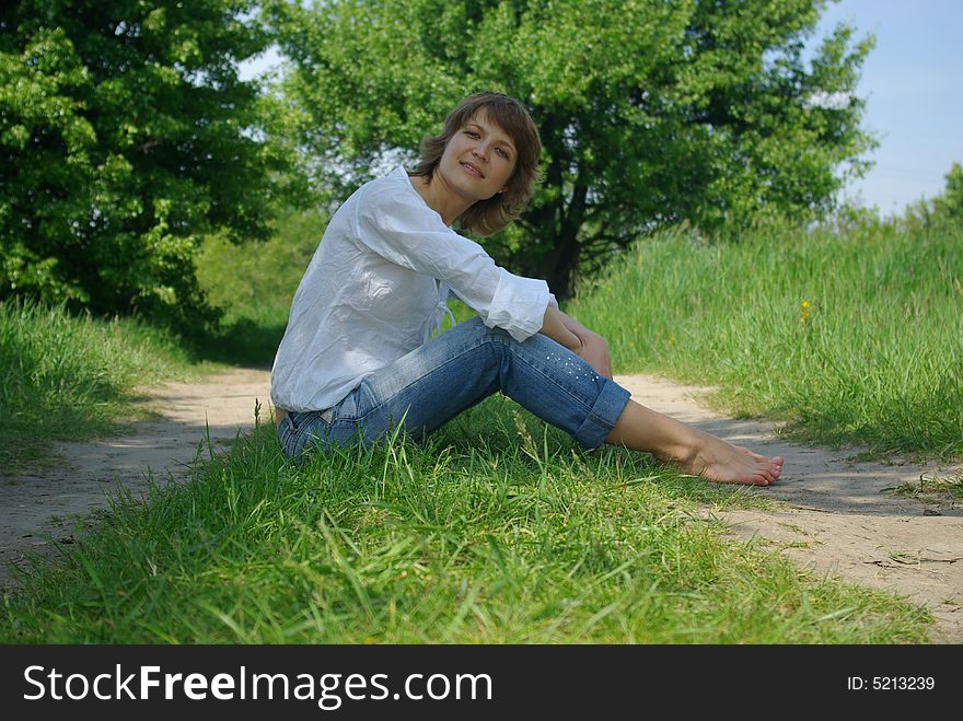 A young attractive woman sitting in a path on a warm summer day