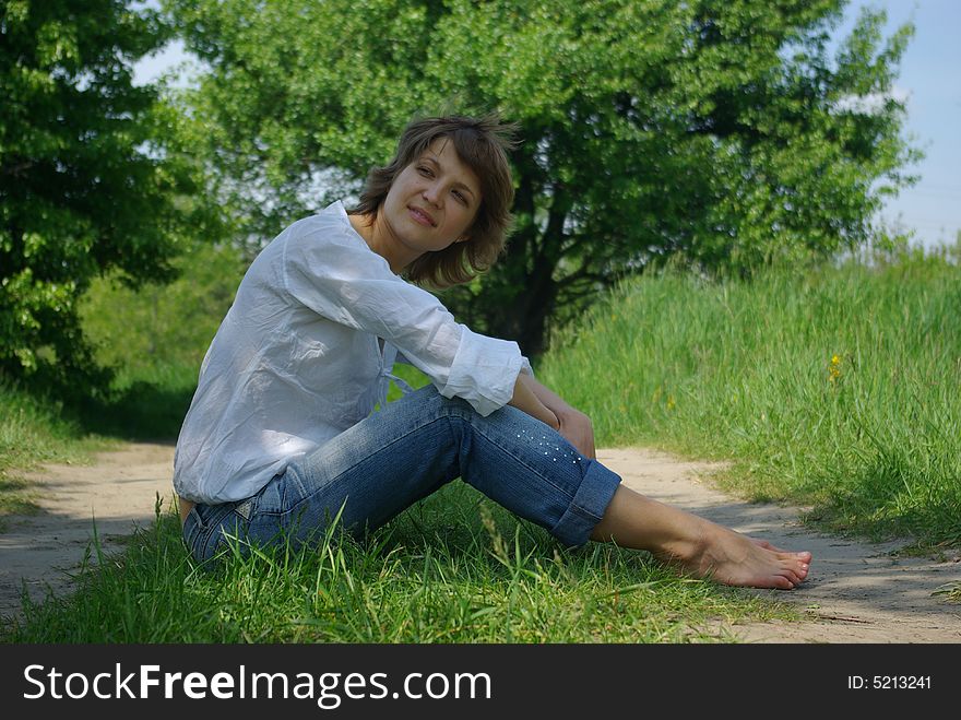 A young attractive woman sitting in a path on a warm summer day