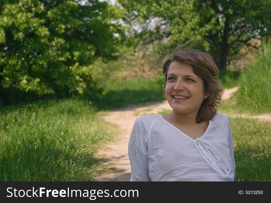 A young attractive woman sitting in a path on a warm summer day