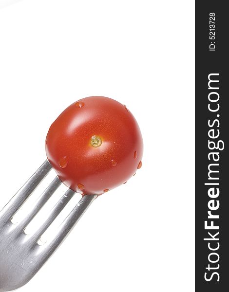 Fresh red juicy tomato with water droplets on a fork