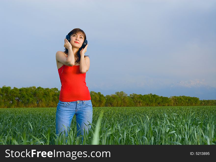 Pretty young woman with headphones in a wheat field