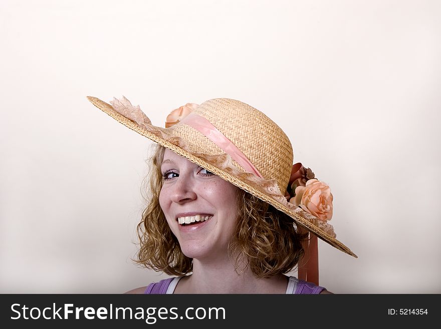 A young blonde woman smiling in a straw flowered hat. A young blonde woman smiling in a straw flowered hat