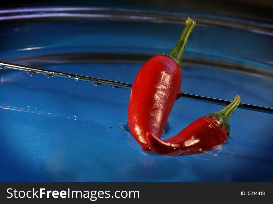 Two red chili peppers on water. Two red chili peppers on water
