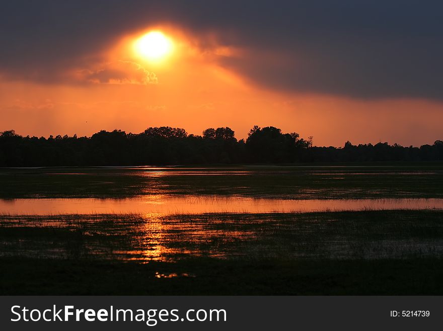 Sunset over meadow with pools of water