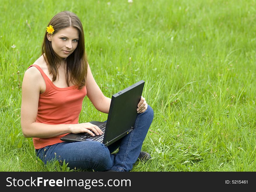 Young business woman relaxing, working on laptop computer on meadow.