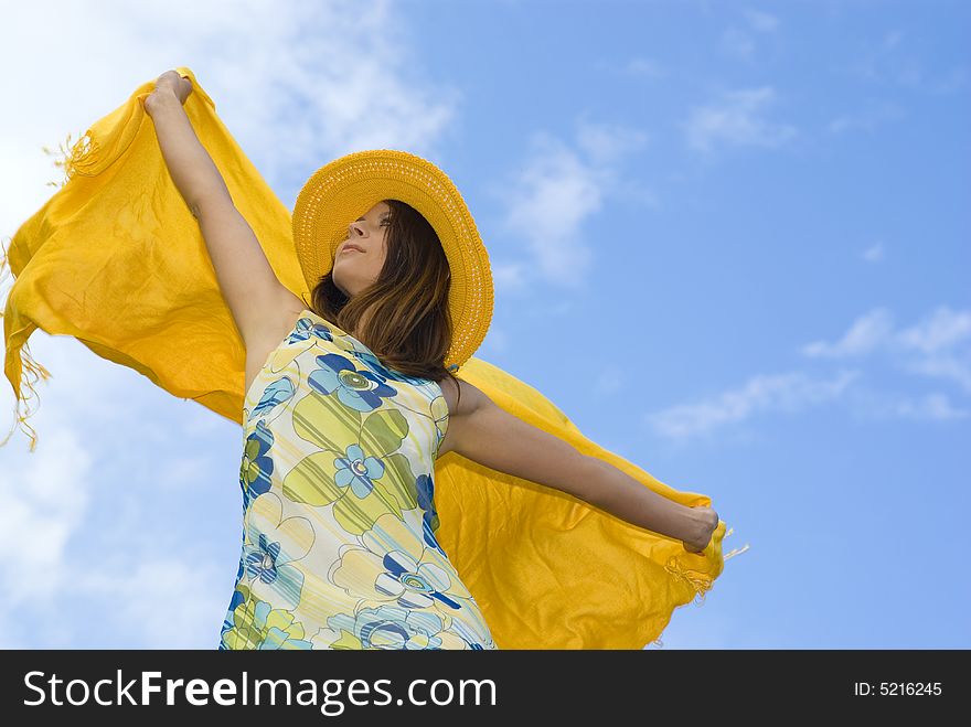 Young woman holding orange wrap against blue sky.