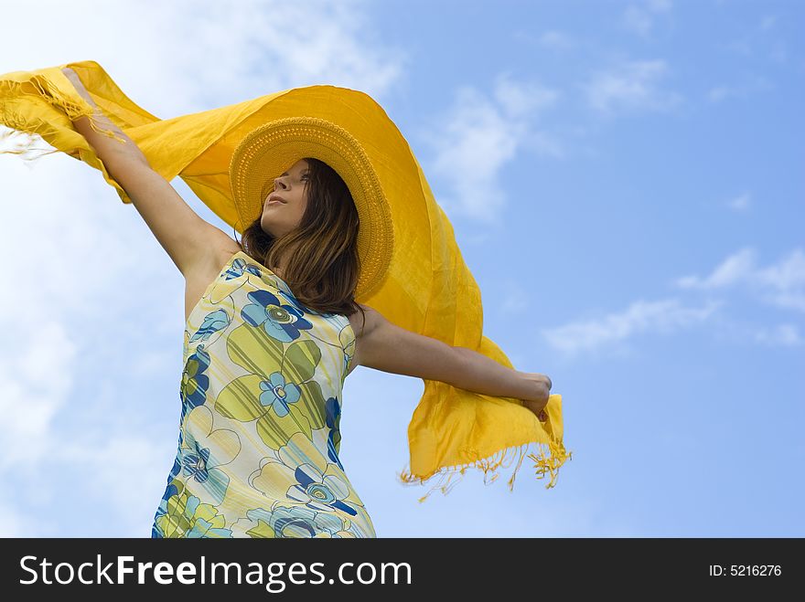 Young woman holding orange wrap against blue sky