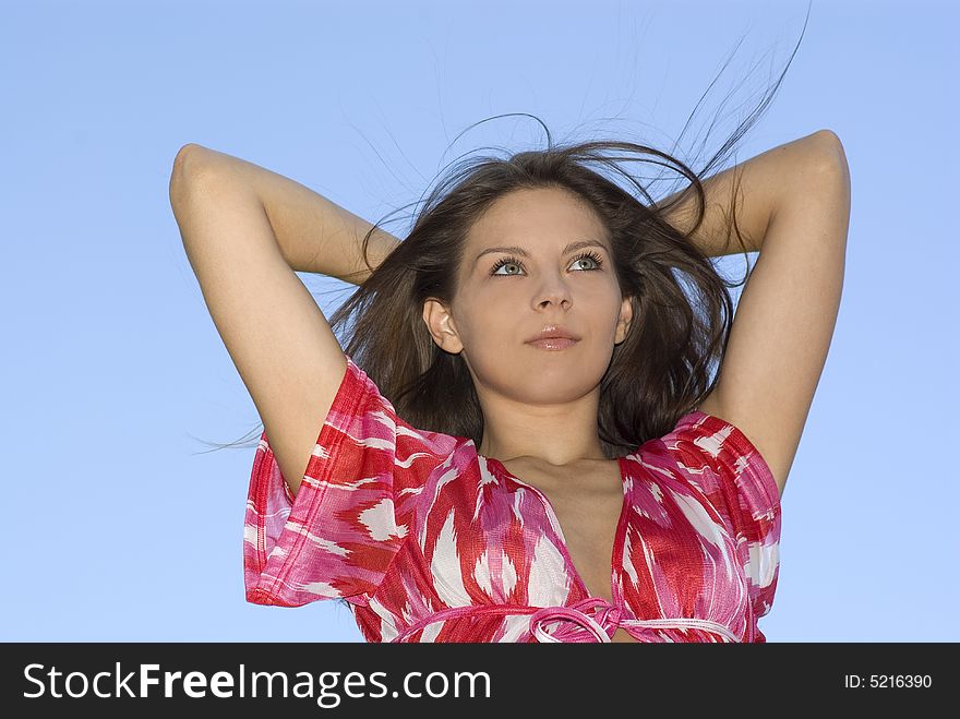 Attractive brunette woman on sky background.
