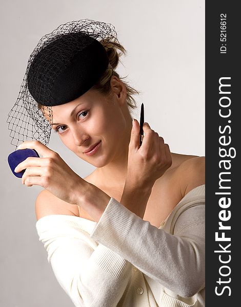 Caucasian retro-styled model applying cosmetics on her face. Caucasian retro-styled model applying cosmetics on her face