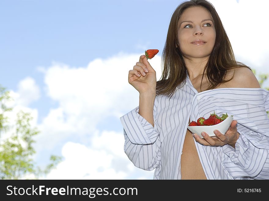 Pretty girl relaxing on balcony and eat red fresh strawberry