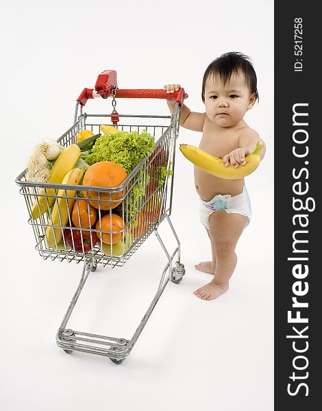 Baby pushes a shopping cart with fruit and vegetables