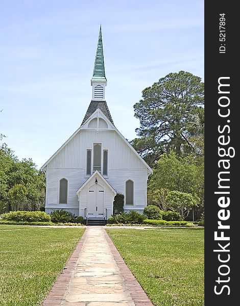 A brick path through a green lawn to a small white church. A brick path through a green lawn to a small white church