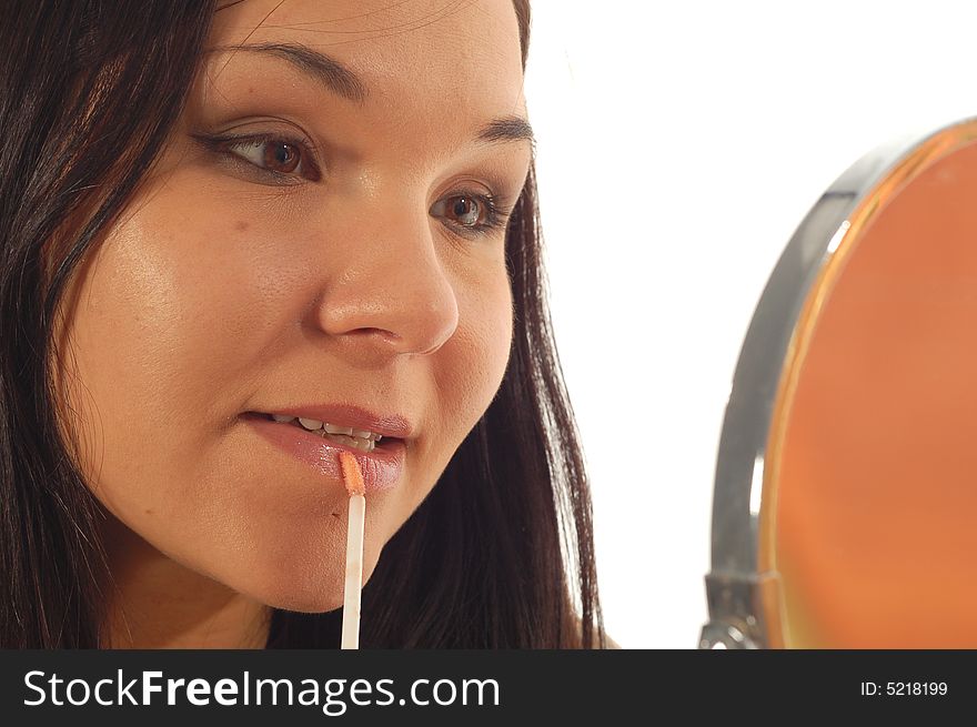 Attractive brunette woman doing makeup on white background