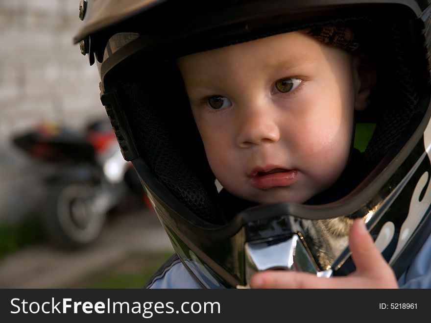 Little boy with helmet, and in back motorcycle