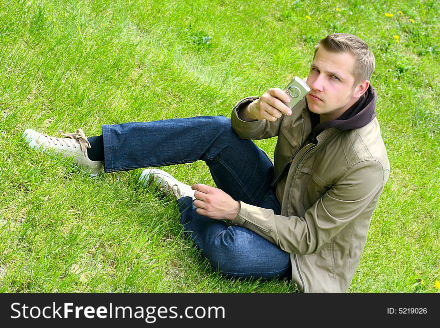 man on green grass with phone in hands