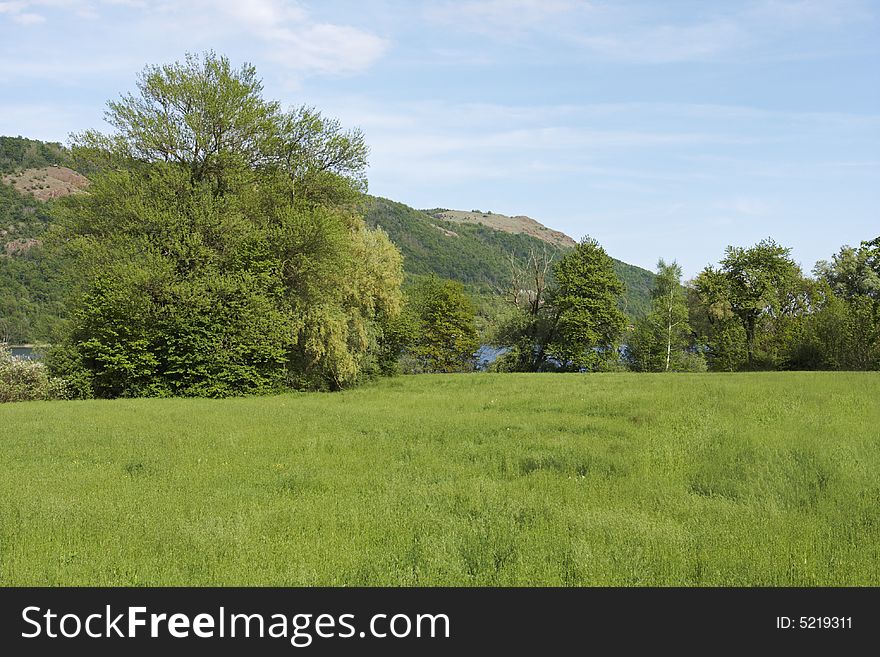 A meadow in spring overlooks a lake bordered by hills and trees. Avigliana, Italy. A meadow in spring overlooks a lake bordered by hills and trees. Avigliana, Italy.