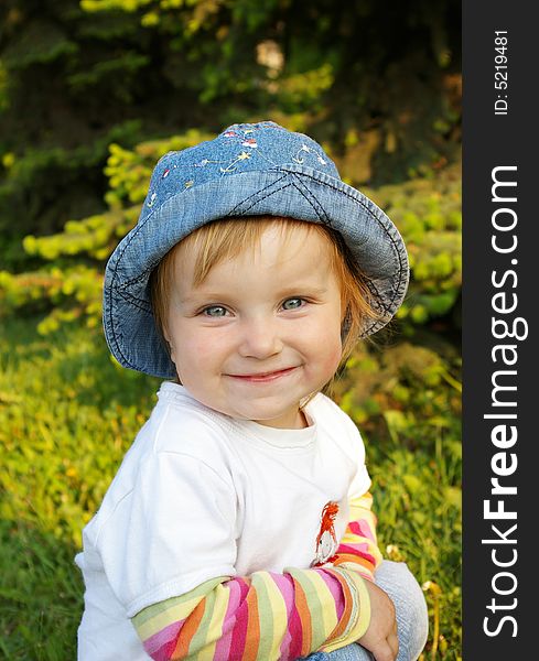 The small beautiful girl sits on a grass and smiles. The small beautiful girl sits on a grass and smiles