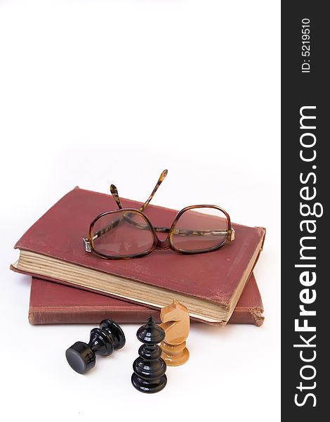 Chess pieces with old book and eyeglasses isolated