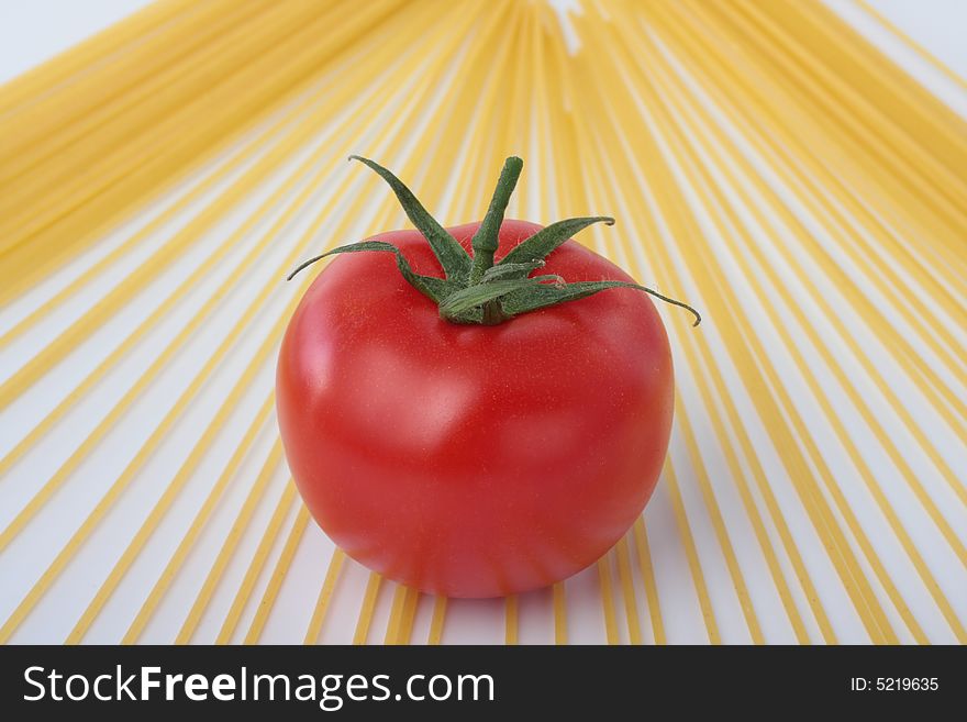 Some spaghetti and a red tomato on a white background. Some spaghetti and a red tomato on a white background