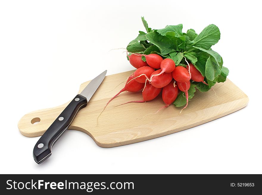 Fresh radishes with knife on chopping board.