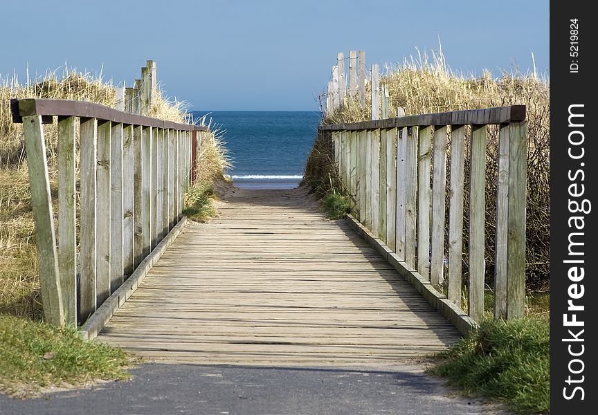 Wooden boardwalk leading to blue sea and beach. Wooden boardwalk leading to blue sea and beach.