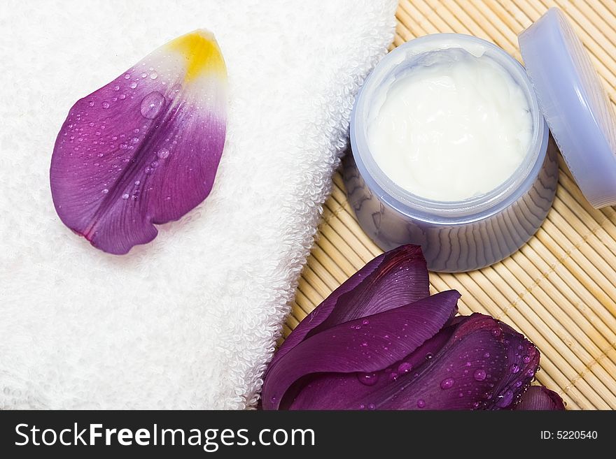 Spa essentials (cream, white towel and violet flower)